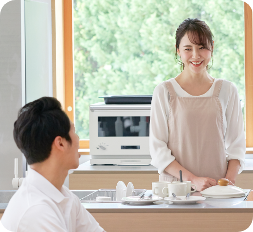 キッチンで笑顔で会話する夫婦の画像